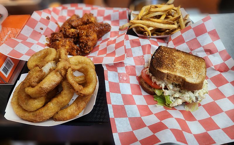 Wings, onion rings, fries, and a sandwich served in red-checkered baskets