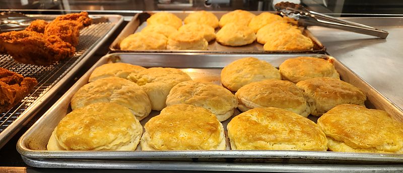 Trays of golden biscuits next to fresh fried chicken in the warmer