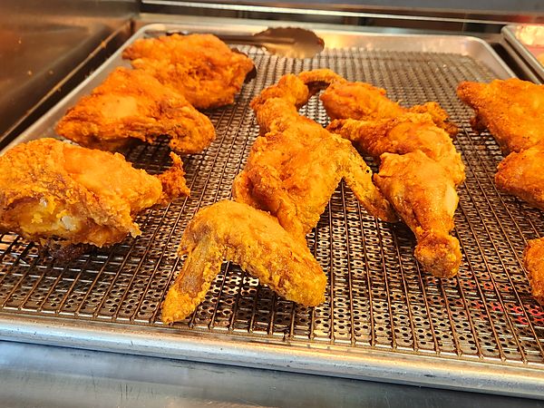 Golden fried chicken resting on a wire rack at The Shack