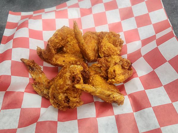 Fried wings piled on red-checkered paper